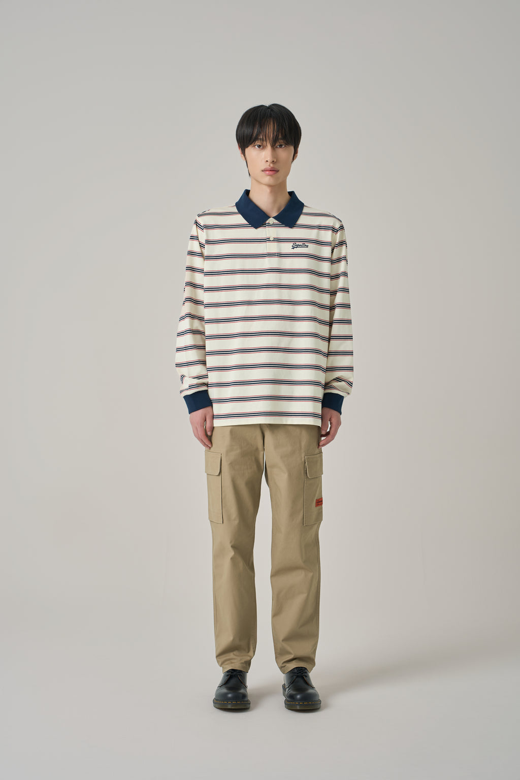 Person wearing a striped sweater and beige pants on a plain background